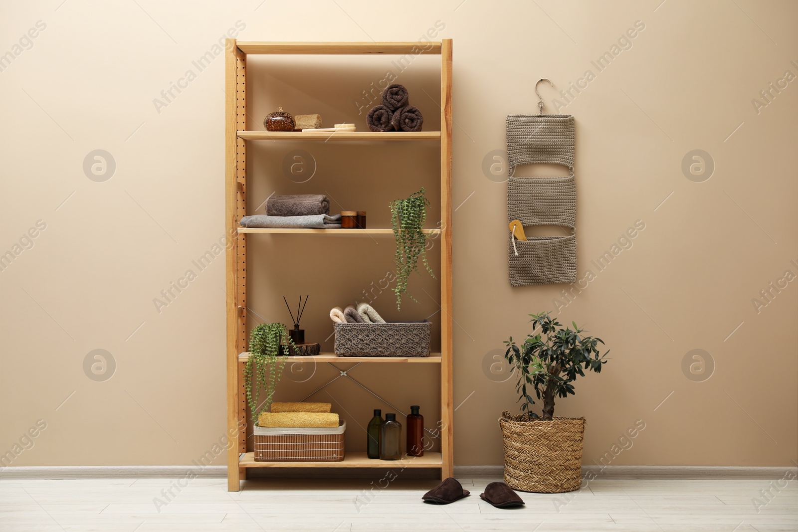 Photo of Shelving unit with soft towels, plants and bottles indoors