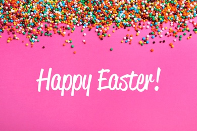 Text Happy Easter and colorful sprinkles on pink background, flat lay. Confectionery decor