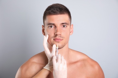Photo of Man getting facial injection on grey background. Cosmetic surgery