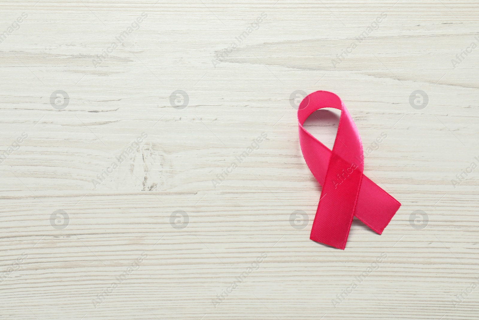 Photo of Breast cancer awareness. Pink ribbon on white wooden table, top view. Space for text