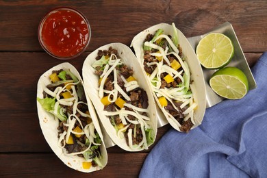 Photo of Delicious tacos with fried meat, cheese and lime on wooden table, flat lay
