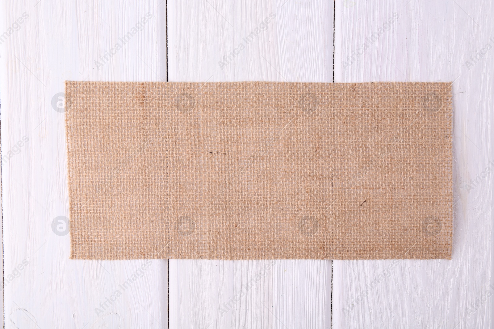 Photo of Piece of burlap fabric on white wooden table, top view. Space for text