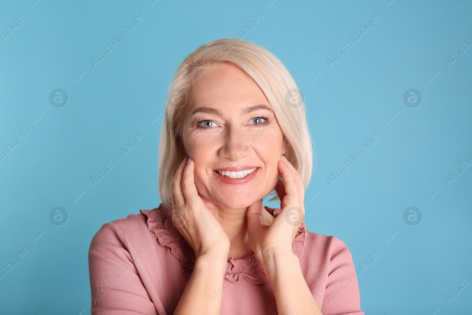 Photo of Portrait of charming mature woman with healthy beautiful face skin and natural makeup on blue background