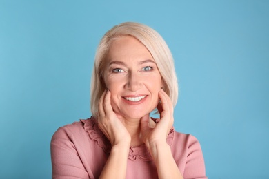 Portrait of charming mature woman with healthy beautiful face skin and natural makeup on blue background