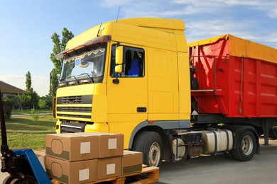 Image of Modern manual forklift with cardboard boxes near truck outdoors on sunny day