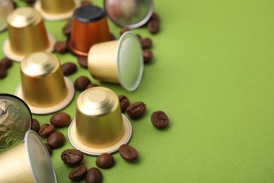 Photo of Many coffee capsules and beans on green background, closeup. Space for text