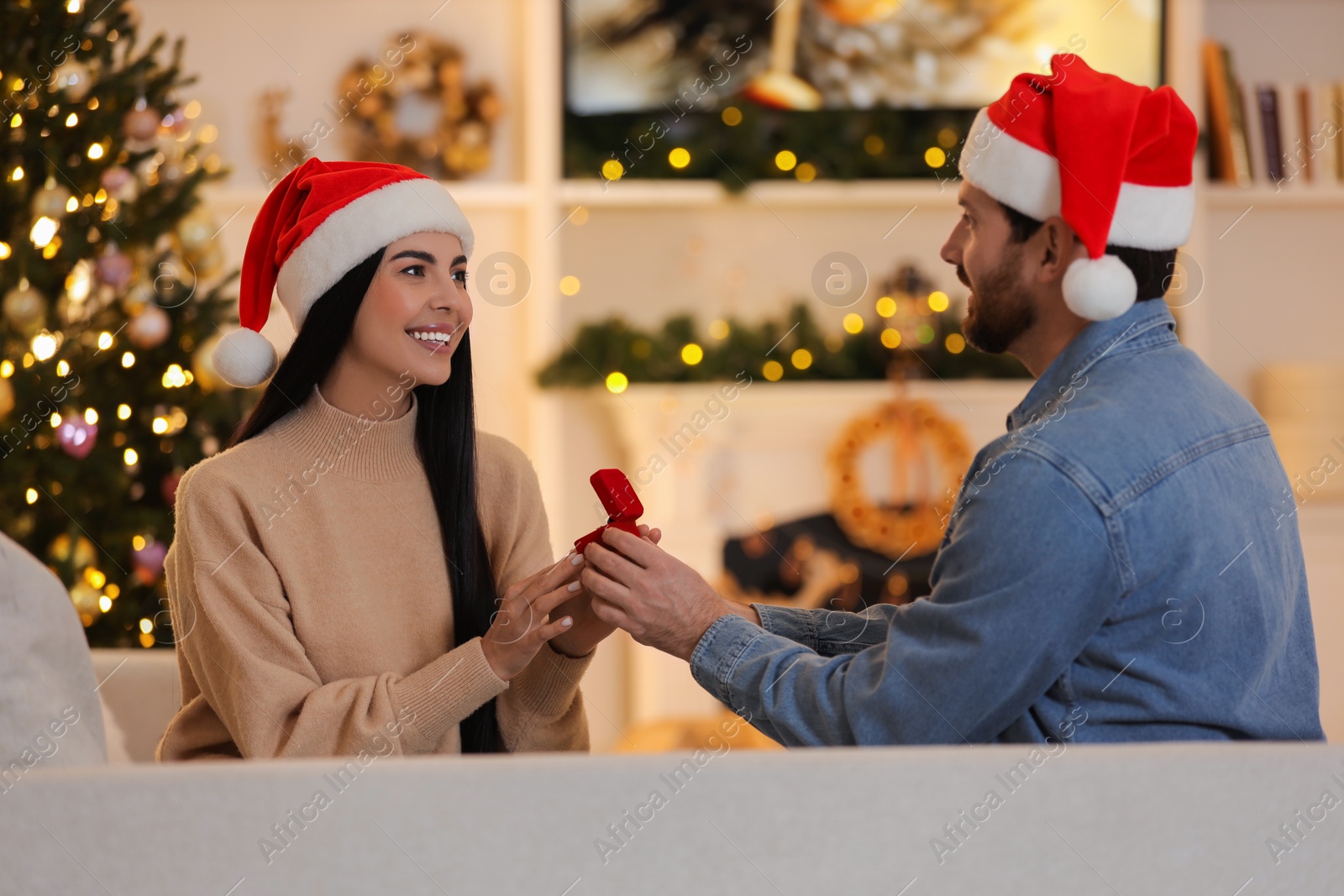 Photo of Man with engagement ring making proposal to his girlfriend at home on Christmas