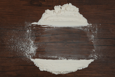 Photo of Flour on wooden background, top view. Space for text
