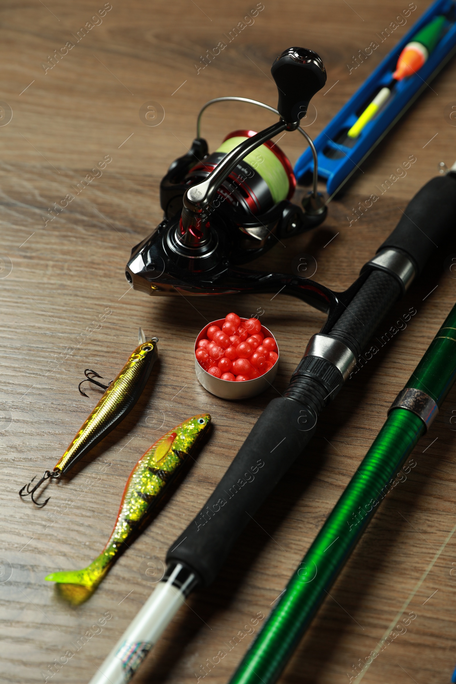 Photo of Spinning rods and fishing tackle on wooden background, closeup