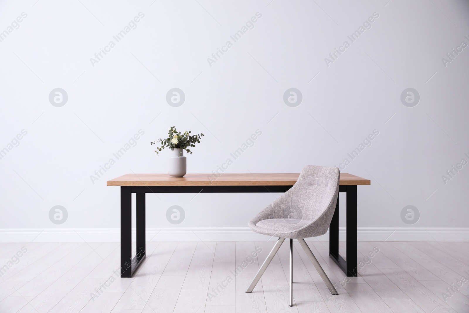 Photo of Table and chair near white wall in room. Stylish interior design