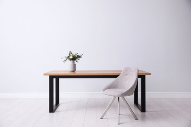Photo of Table and chair near white wall in room. Stylish interior design