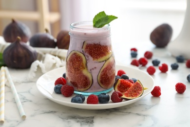 Photo of Delicious fig smoothie in glass jar on white marble table
