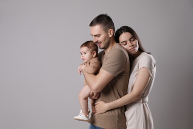 Happy family. Couple with their cute baby on grey background, space for text