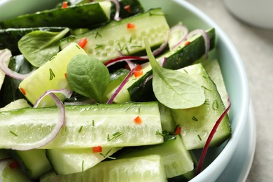 Photo of Delicious cucumber salad with onion and spinach in bowl, closeup