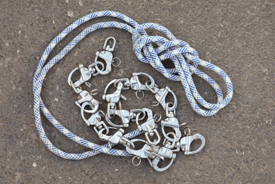 Photo of Climbing rope with carabiners on asphalt, top view