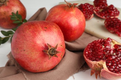 Photo of Fresh pomegranates and seeds on white table, closeup