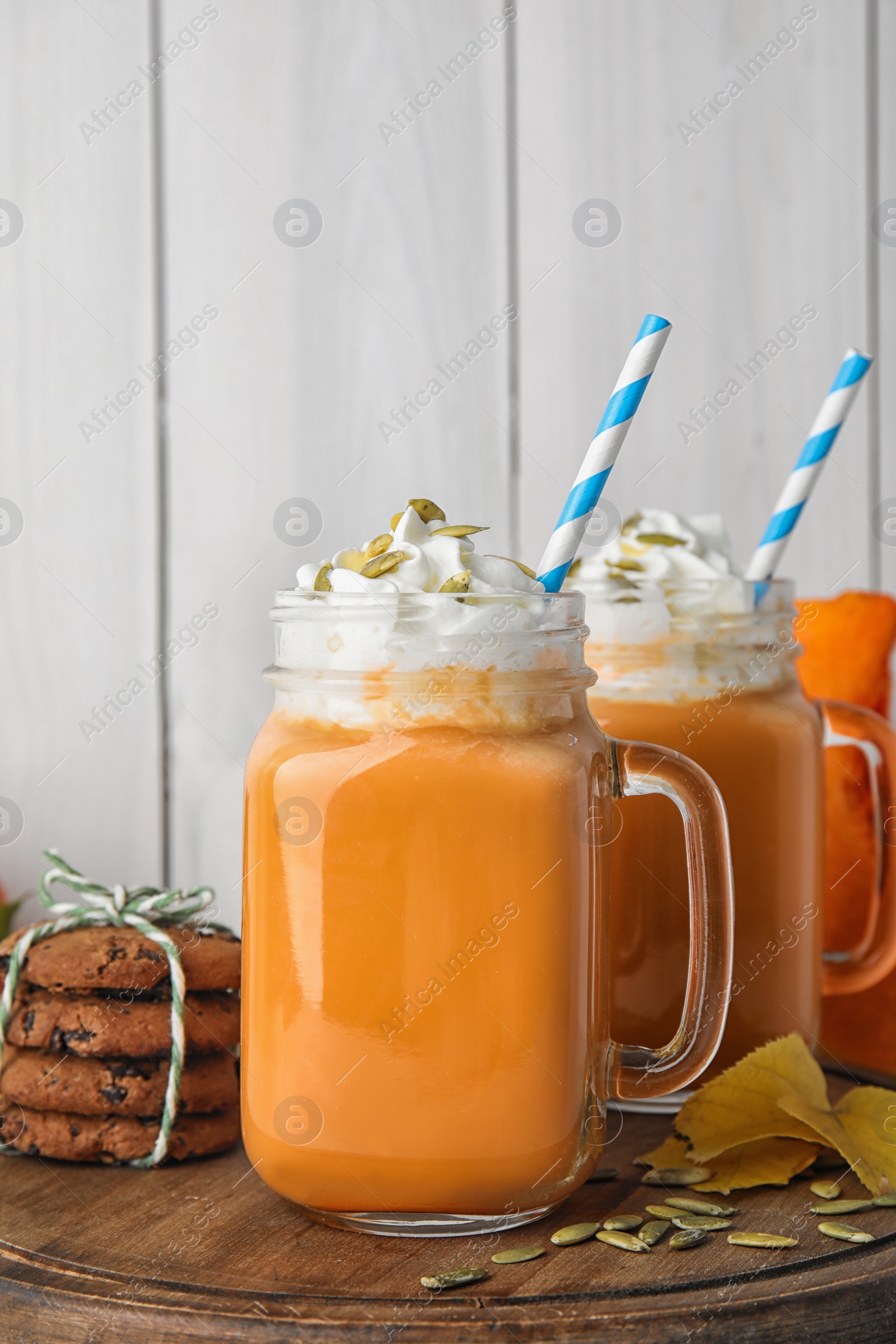 Photo of Mason jars with pumpkin spice latte and whipped cream on wooden board