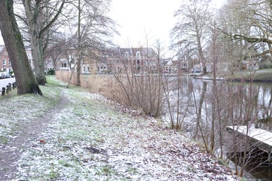 Photo of Picturesque view of water canal, trees and buildings on winter day