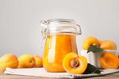Photo of Jar of apricot jam and fresh fruits on table