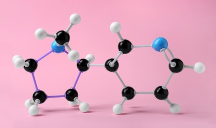 Molecule of nicotine on pink background. Chemical model