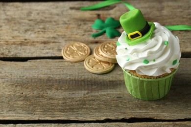 St. Patrick's day party. Tasty cupcake with green leprechaun hat topper on wooden table, closeup. Space for text