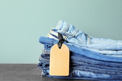 Photo of Stack of jeans on table against color background