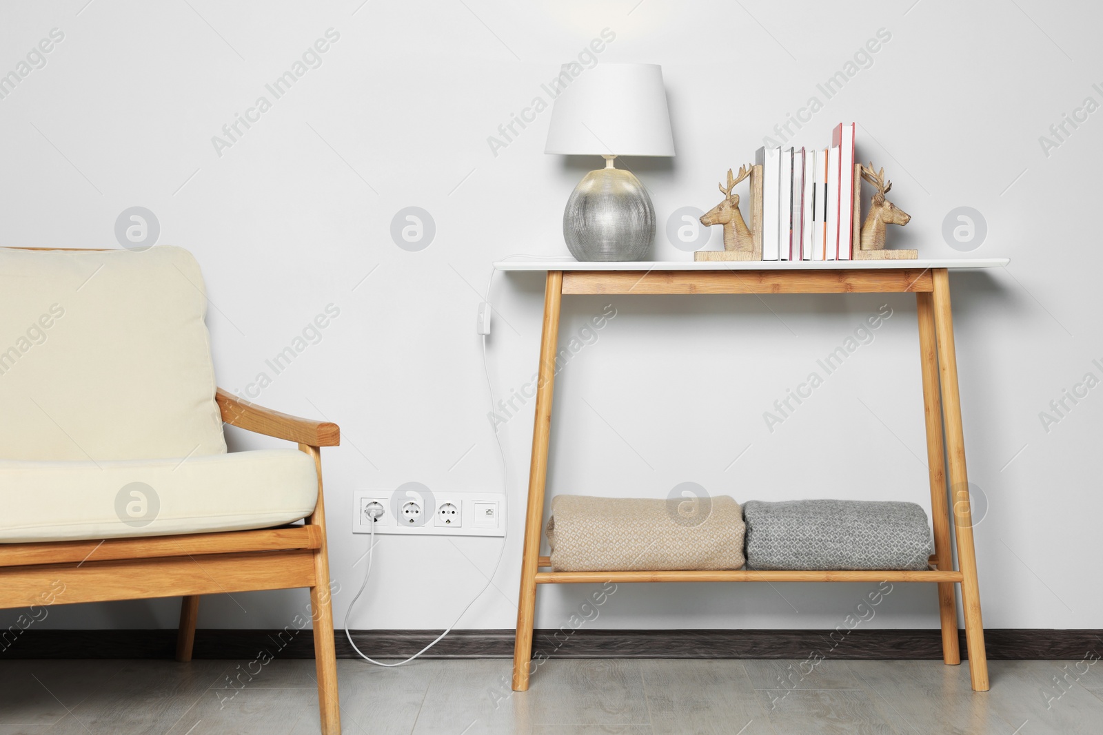 Photo of Lamp with books on wooden table against white wall