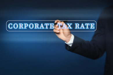Corporate tax rate. Man writing on virtual screen against color background, closeup