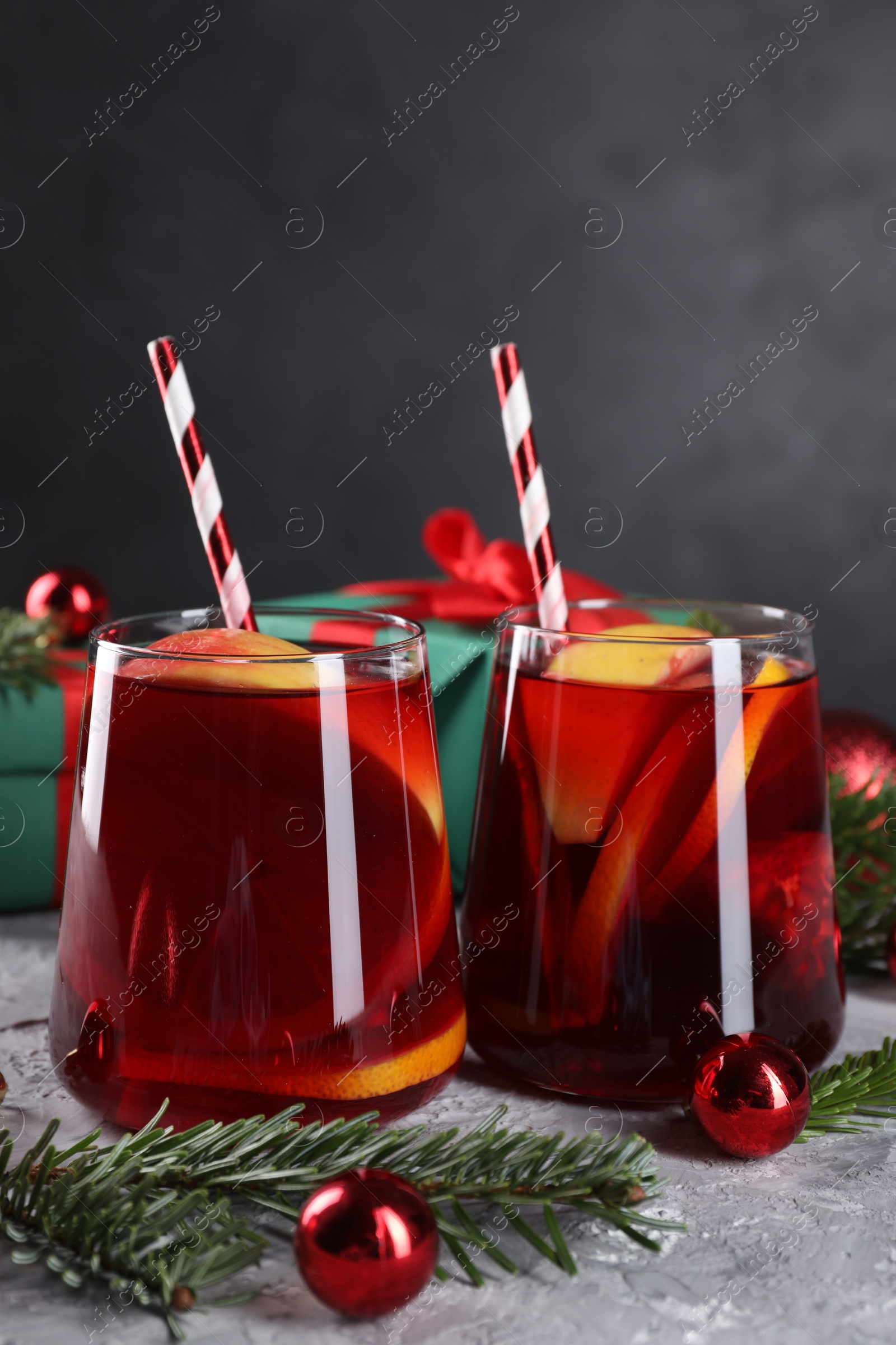 Photo of Delicious Sangria drink in glasses and Christmas decorations on grey textured table, closeup