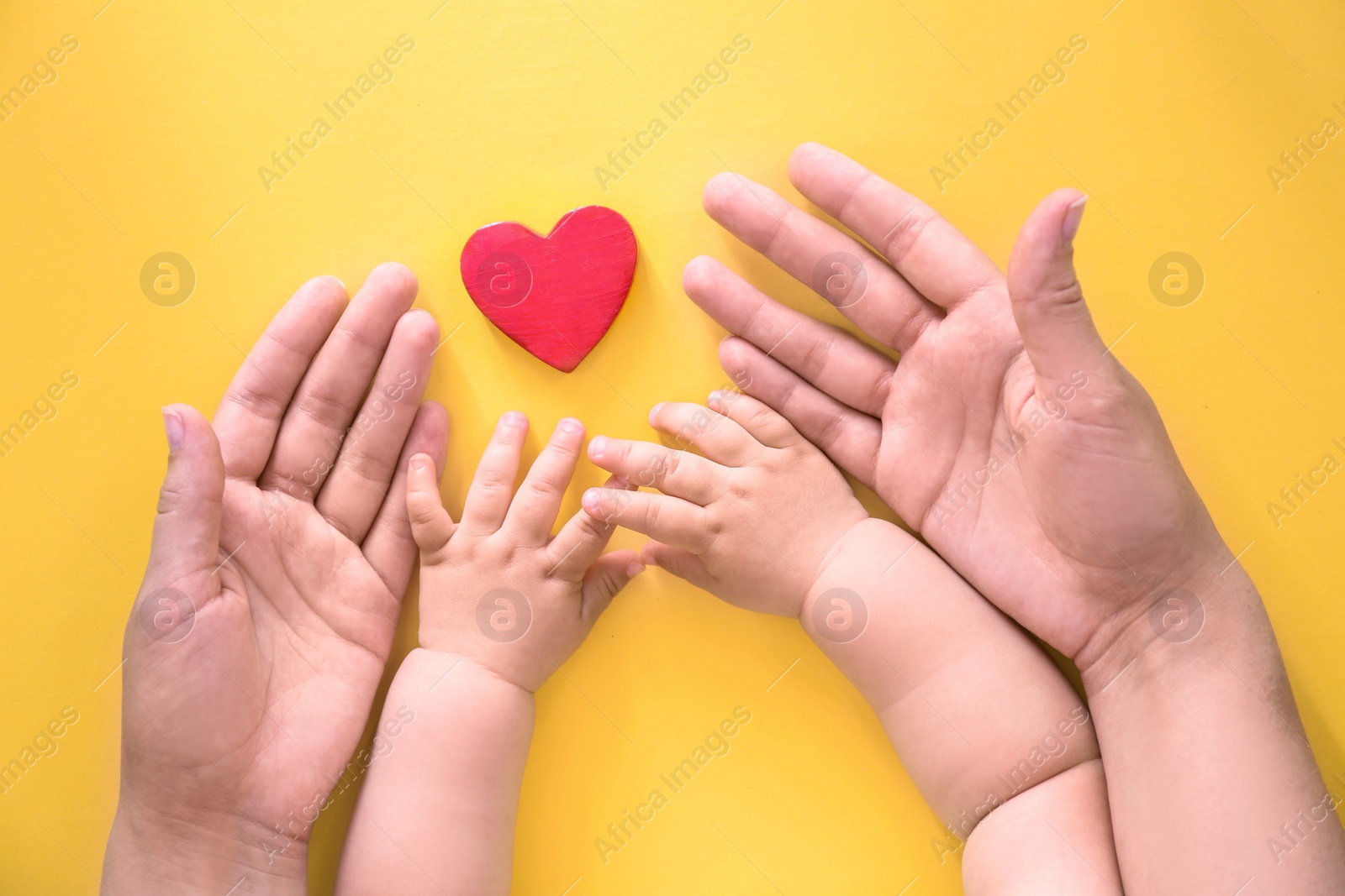 Photo of Young woman and child protecting red heart on color background, top view