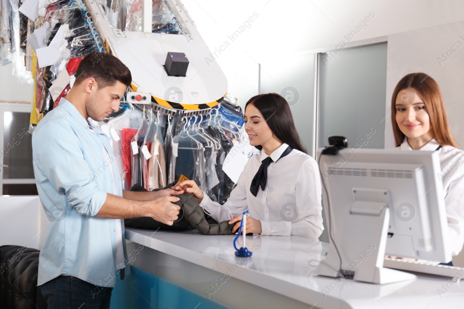 Photo of Female employees working with client at dry-cleaner's