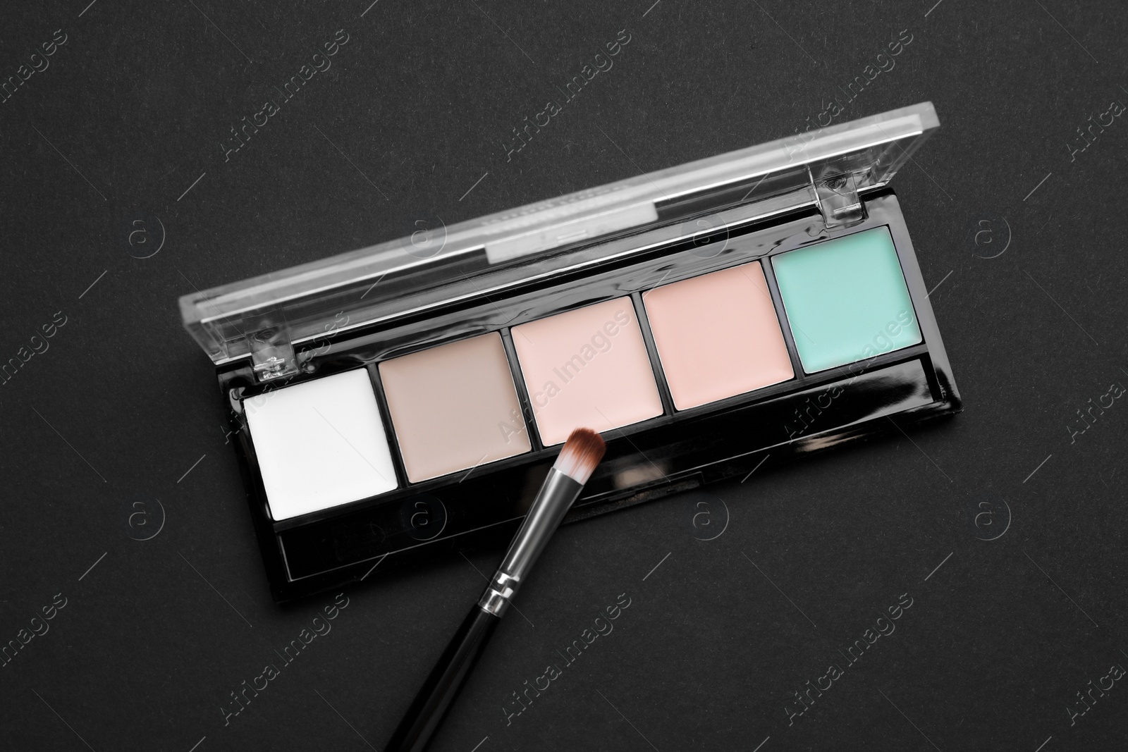 Photo of Contouring palette and brush on black background, top view. Professional cosmetic product