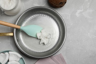 Photo of Frying pan with coconut oil and spatula on light grey table, flat lay