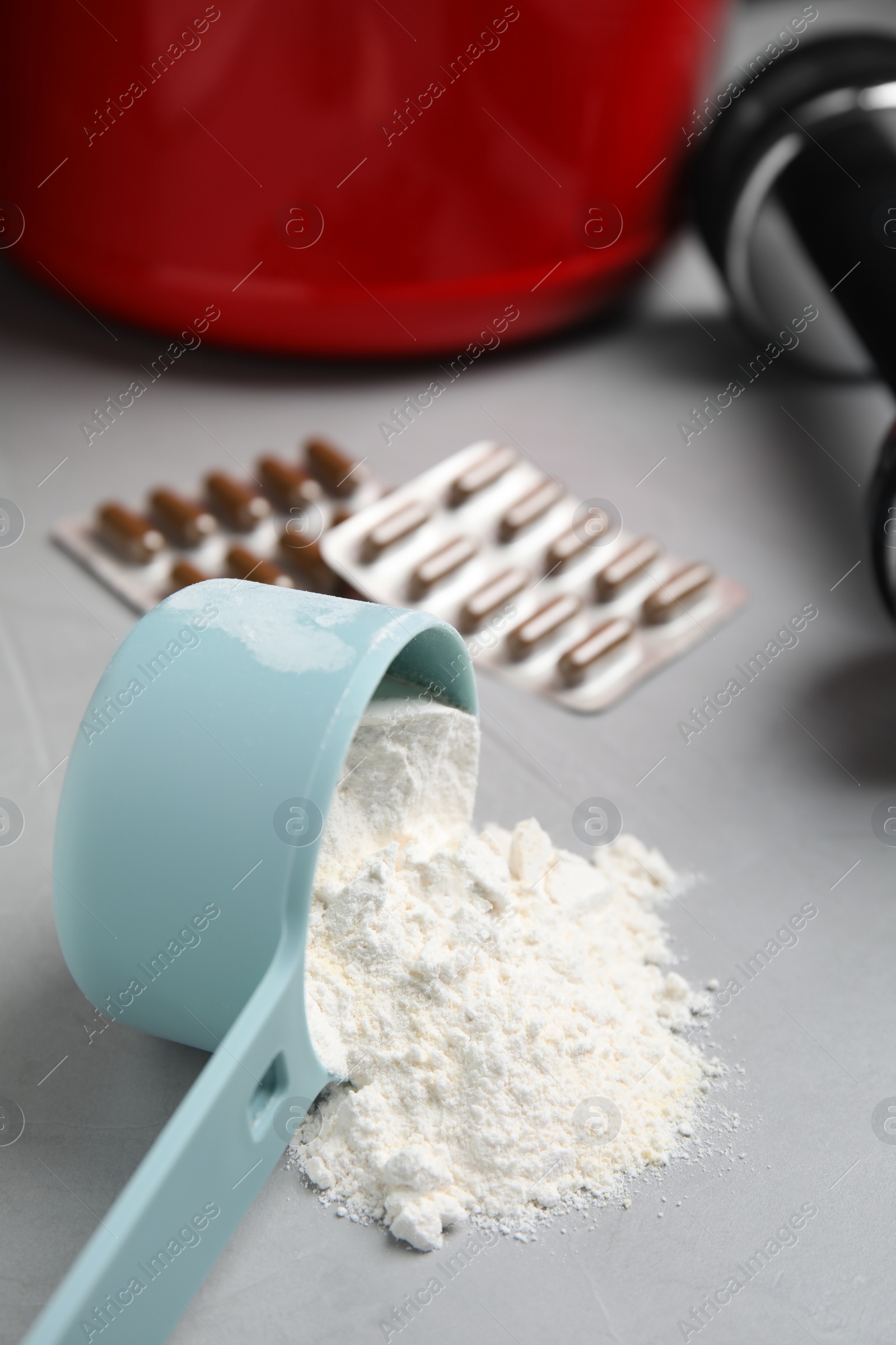 Photo of Measuring scoop of amino acids powder on light grey table