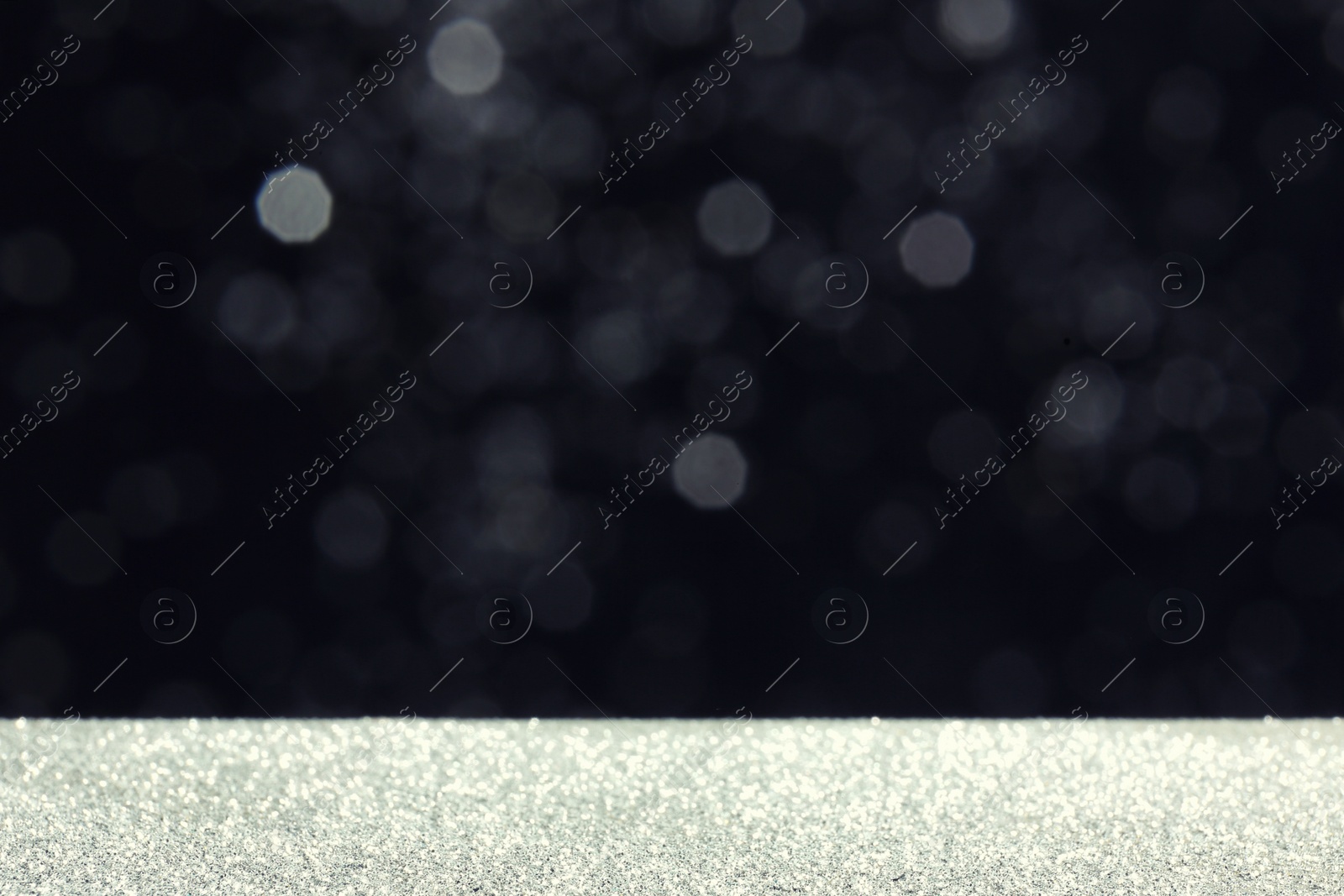 Photo of Glitter on table against dark background. Bokeh effect