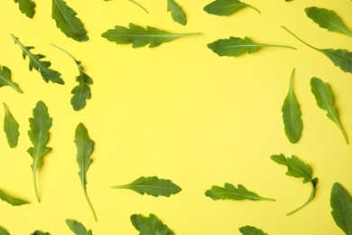 Photo of Frame of fresh arugula leaves on yellow background, flat lay. Space for text