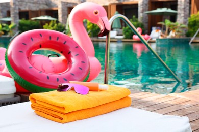 Beach accessories on sun lounger, inflatable ring and float near outdoor swimming pool at luxury resort