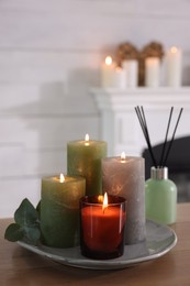 Photo of Beautiful burning candles and air freshener on wooden table indoors, space for text