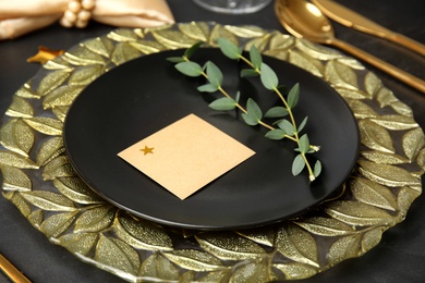 Elegant festive table setting with blank card on black background, closeup