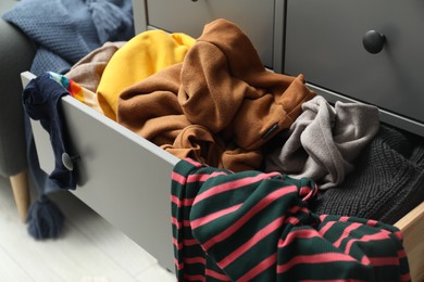 Cluttered chest of drawers indoors, closeup. Clothes in mess