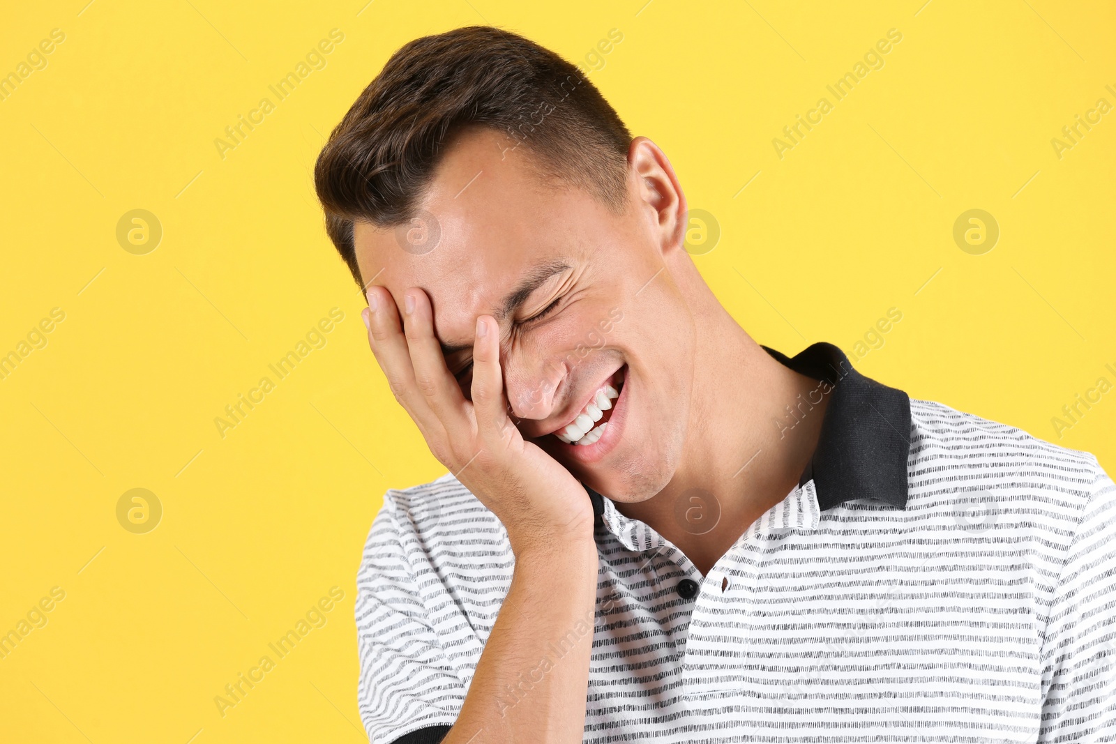 Photo of Portrait of handsome young man laughing on color background