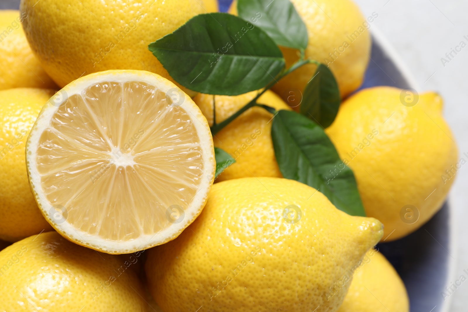 Photo of Fresh lemons and green leaves on table, closeup