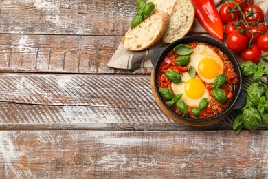 Photo of Delicious Shakshuka served on wooden table, flat lay. Space for text