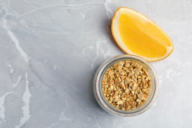 Jar of dried orange zest seasoning and fresh fruit on light grey table, flat lay. Space for text