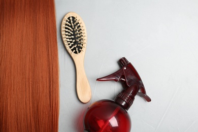 Photo of Flat lay composition with red hair and hairdresser's tools on light background. Space for text
