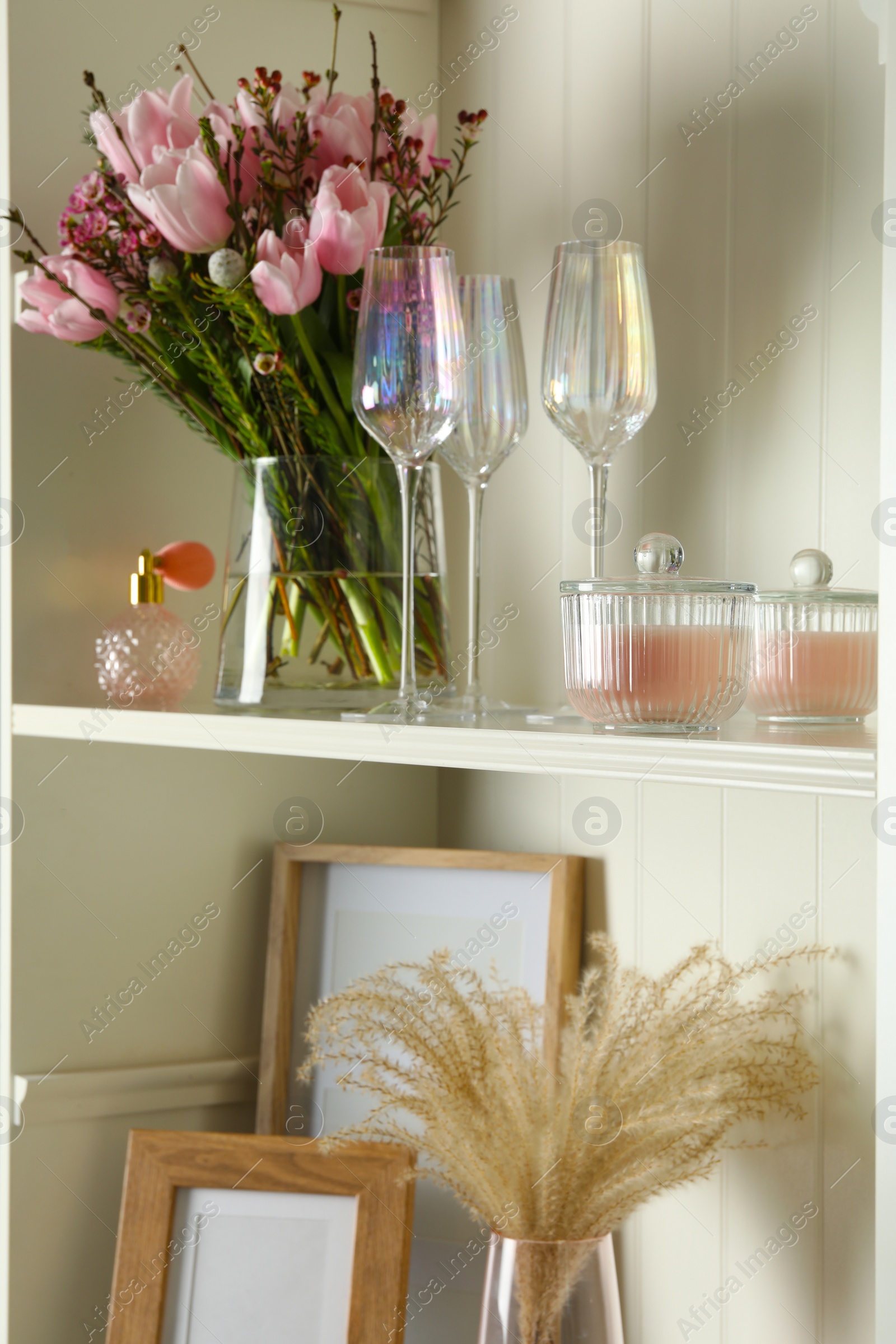 Photo of White shelving unit with glassware and different decorative elements