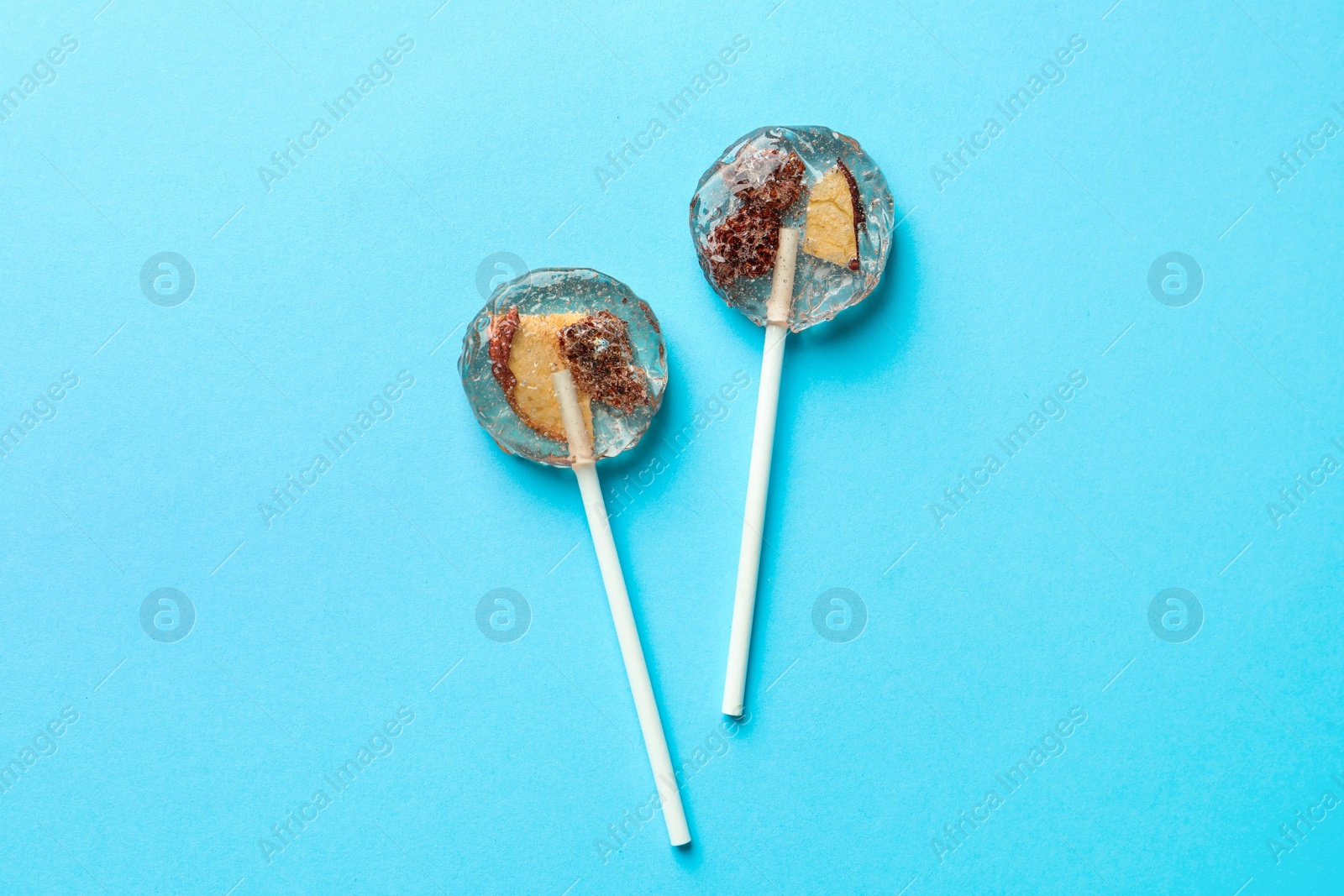 Photo of Sweet colorful lollipops with berries on light blue background, flat lay