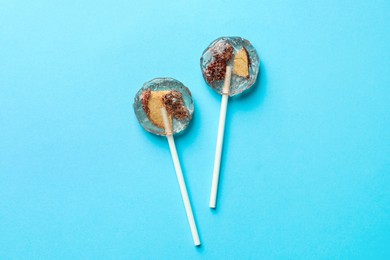 Photo of Sweet colorful lollipops with berries on light blue background, flat lay