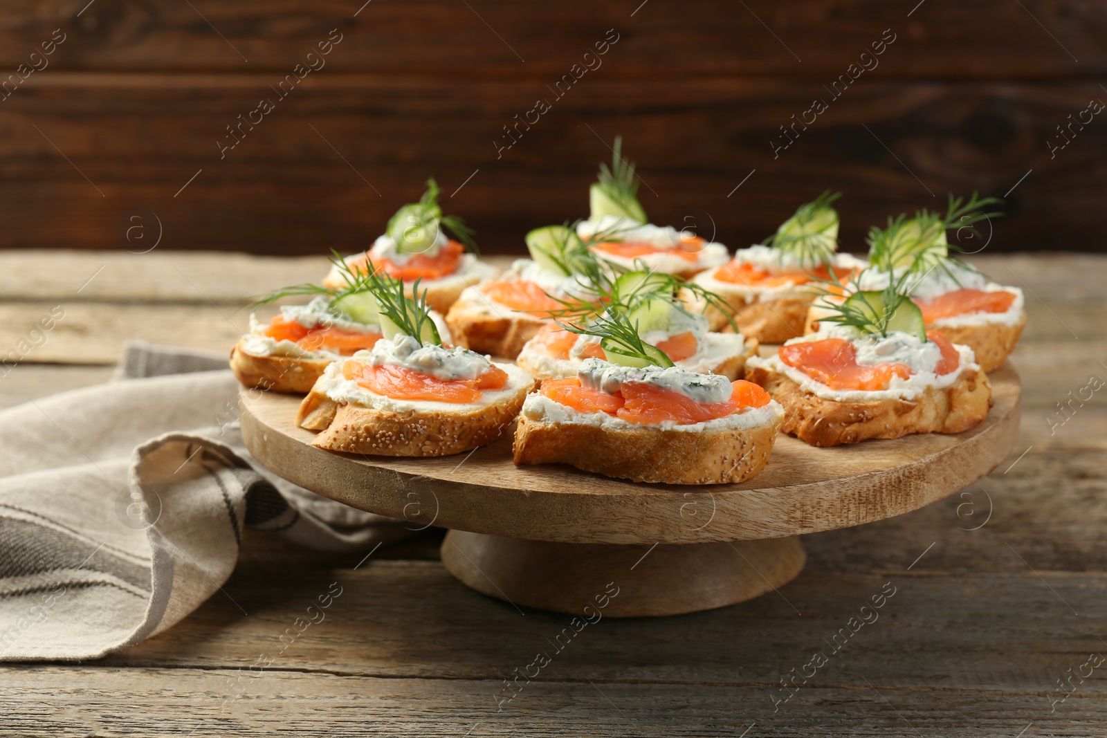 Photo of Tasty canapes with salmon, cucumber, cream cheese and dill on wooden table