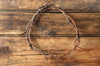 Photo of Crown of thorns on wooden background, top view. Easter attribute